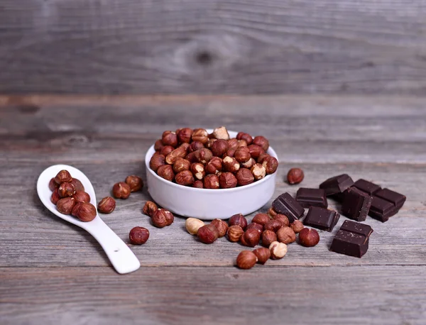 Fresh hazelnut and dark chocolate on wood — Stock Photo, Image