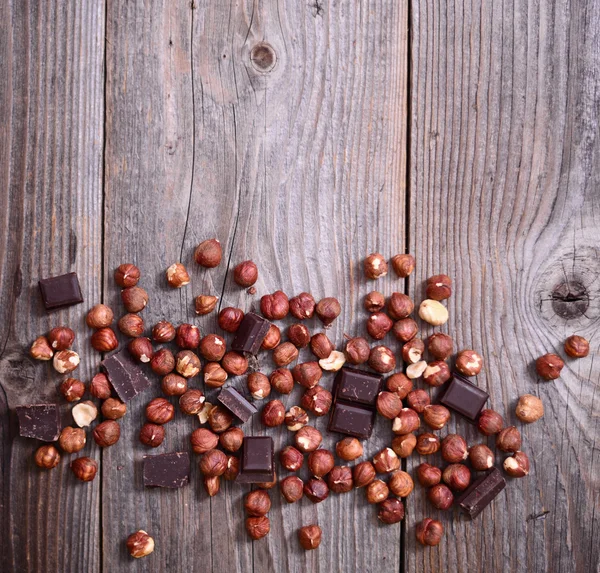 Fresh hazelnut and dark chocolate on wooden background — Stock Photo, Image