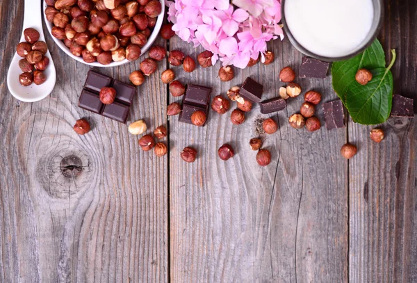 Hazelnut segar dan coklat gelap pada latar belakang kayu — Stok Foto