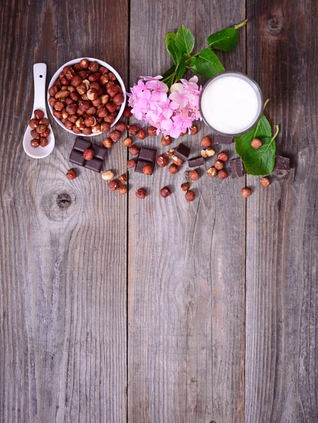 Avellana fresca, leche y chocolate negro sobre mesa de madera — Foto de Stock