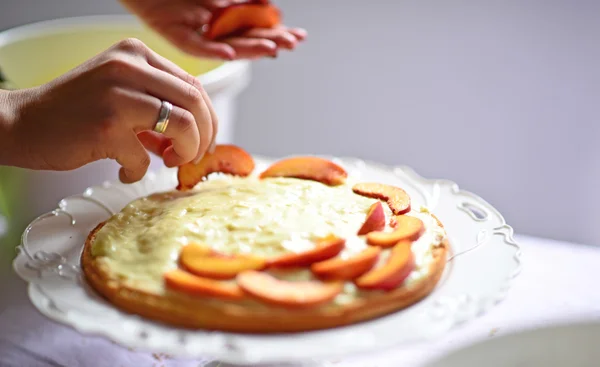 Mujer mano poner melocotón fresco en la corteza de la torta — Foto de Stock