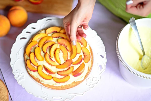 Woman hand put fresh peach on the cake crust — Stock Photo, Image