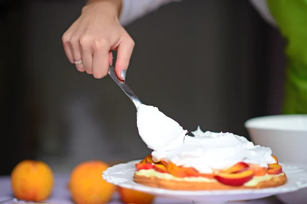 Nő kéz tejszínhabbal fektetni a torta kéreg — Stock Fotó