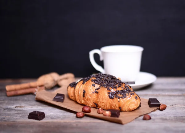 Chocolate croissant and coffee on wooden table — Stock Photo, Image