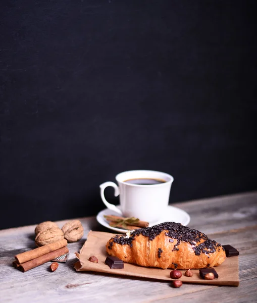 Croissant al cioccolato con caffè su tavolo rustico — Foto Stock