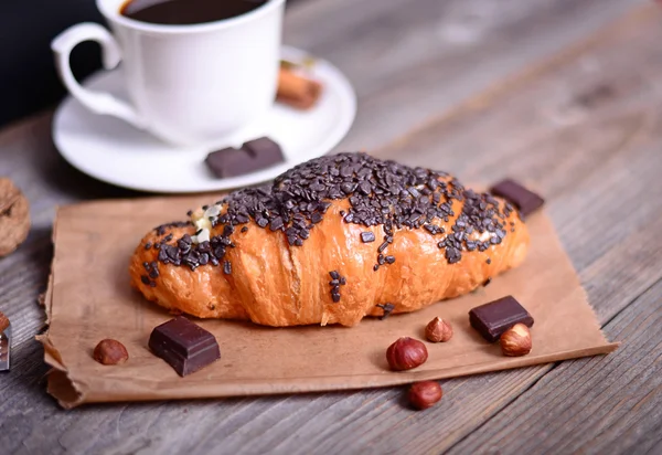 Croissant au chocolat avec café sur fond en bois — Photo