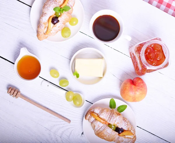 Färsk frukt croissant med kaffe, smör, honung och persika på whi — Stockfoto