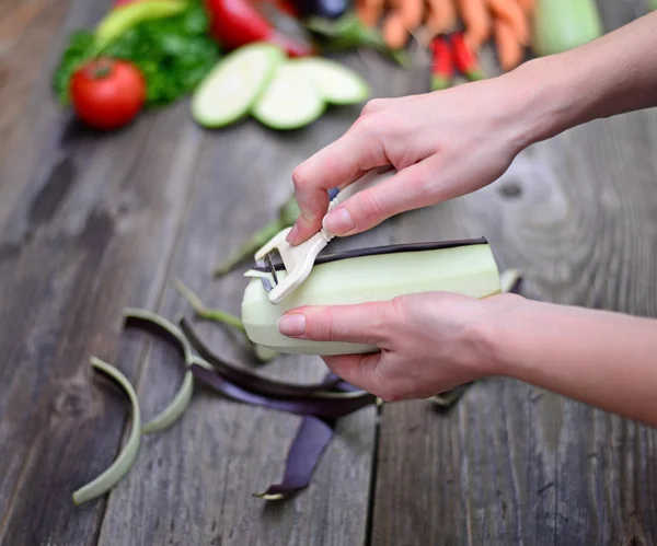 La mano de la mujer pelando berenjena fresca — Foto de Stock