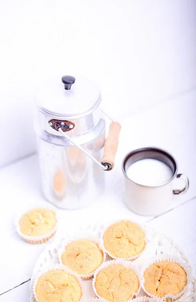 Кукурудзяні кекси та молоко на білому столі — стокове фото