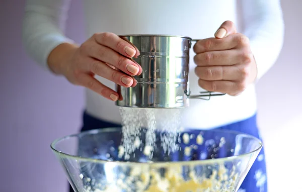 Woman sifting flour into a bowl — Stock Photo, Image