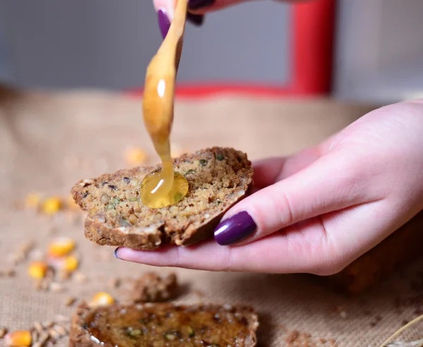 Mujer mano poner la miel en el pan — Foto de Stock