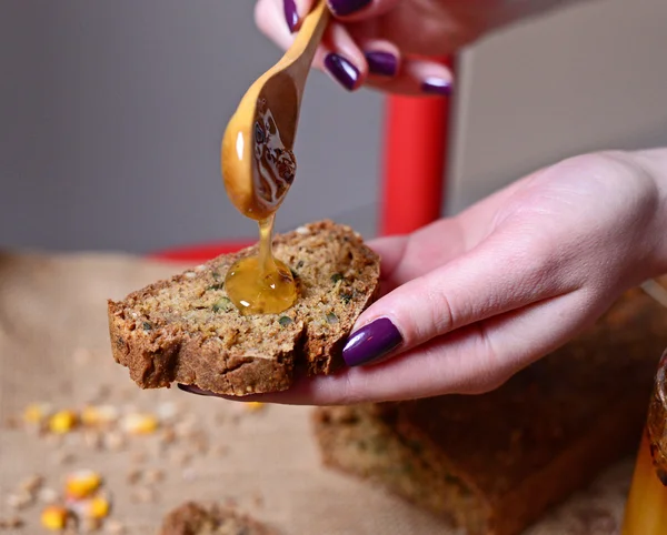 Mujer mano poner la miel en el pan — Foto de Stock