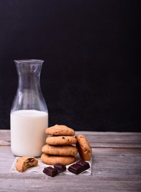 Çikolatalı kurabiye yığını ve yazı tahtası üzerinde süt şişesi