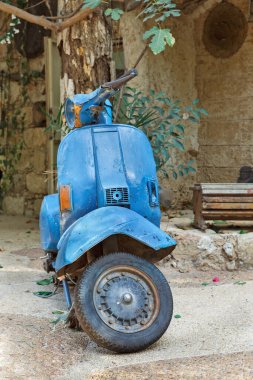 Evin arka planında mavi, eski bir scooter var.