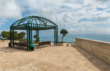 Hayfa 'da bulutların arka planına karşı banklı pergola