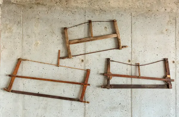 old wooden hand-saw on a concrete wall
