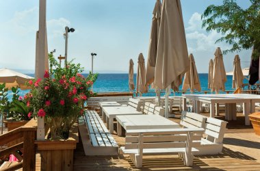 Beyaz masalar ve deniz kenarındaki banklar.