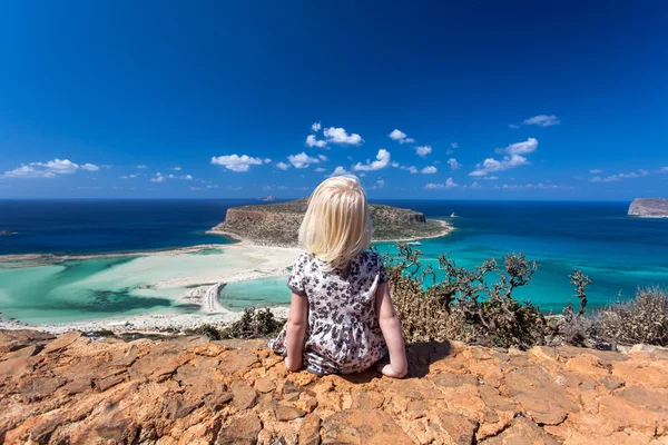 Linda chica sentada en una roca frente a la playa de Balos y la isla Gramvousa en Creta, Grecia — Foto de Stock