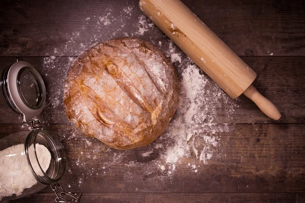 Pane appena sfornato ricoperto di farina su un tavolo di legno — Foto Stock