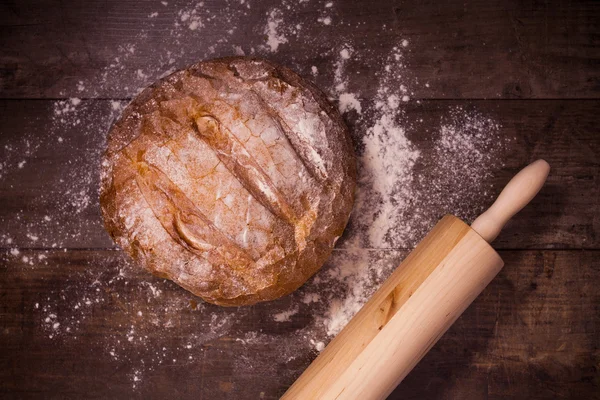 Fresh baked bread covered with flour on a wooden table — Stock Photo, Image