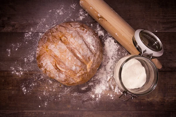 Fresh baked bread covered with flour on a wooden table — Stock Photo, Image