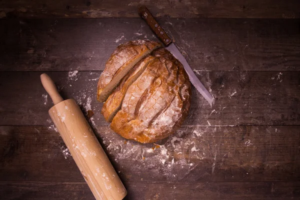 Fresh baked bread covered with flour on a wooden table — Stock Photo, Image