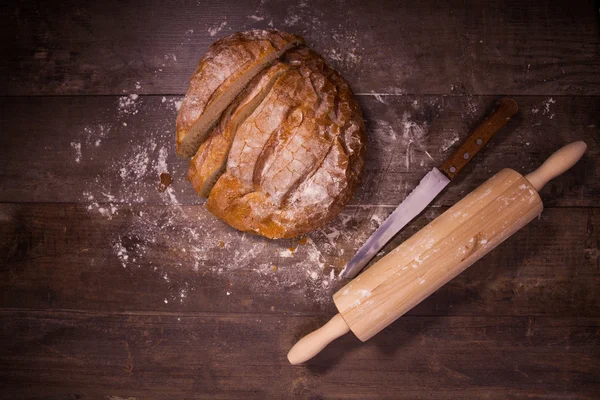 Fresh baked bread covered with flour on a wooden table — Stock Photo, Image