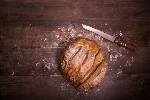 Fresh baked bread covered with flour on a wooden table — Stock Photo, Image