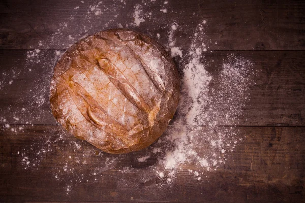 Pane appena sfornato ricoperto di farina su un tavolo di legno — Foto Stock