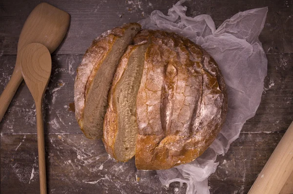 Pan recién horneado cubierto de harina sobre una mesa de madera — Foto de Stock