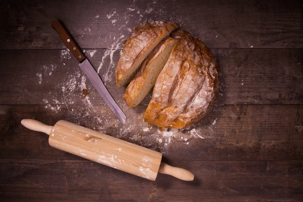 Frisch gebackenes Brot mit Mehl bedeckt auf einem Holztisch — Stockfoto