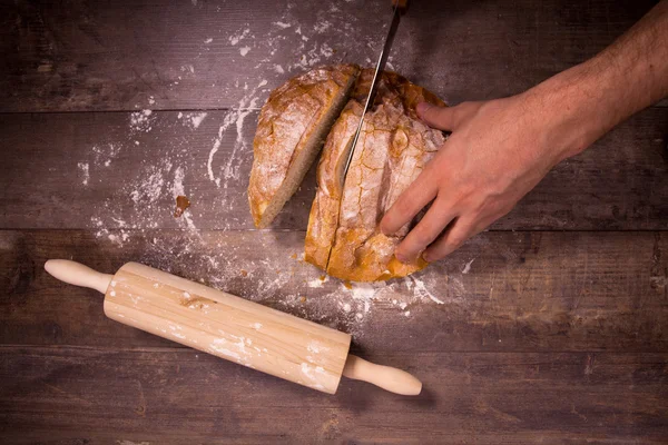 Pão fresco assado coberto com farinha em uma mesa de madeira — Fotografia de Stock