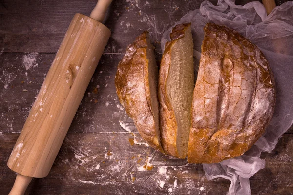 Čerstvý pečený chléb s moukou na dřevěný stůl — Stock fotografie