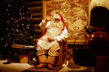 Rovaniemi Finlandiya 25 Temmuz 2000: Noel Baba ofisinde şöminenin yanında oturuyor, yeni yıl ve noel kavramları