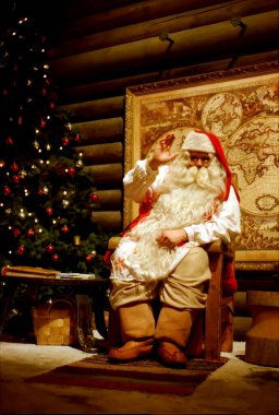 Rovaniemi Finlandiya 25 Temmuz 2000: Noel Baba ofisinde şöminenin yanında oturuyor, yeni yıl ve noel kavramları