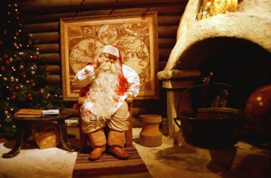 Rovaniemi Finlandiya 25 Temmuz 2000: Noel Baba ofisinde şöminenin yanında oturuyor, yeni yıl ve noel kavramları