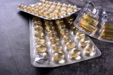 Sarı yumuşak kabuklu D vitamini kapsülleri. Siyah arka planda D vitamini sarı haplar. Tıp konsepti. COVID 'e karşı koruyucu madde - 19 virüs. Coronavirus profilaksi