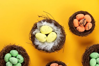 Renkli arka planda yumurtaları olan kuş yuvaları, Paskalya konsepti. Üst görünüm, seçici odak, kopyalama alanı