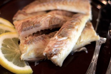 Koyu bir tabakta, limonla süslenmiş balık filetosu. Tuzda pişmiş balık. 
