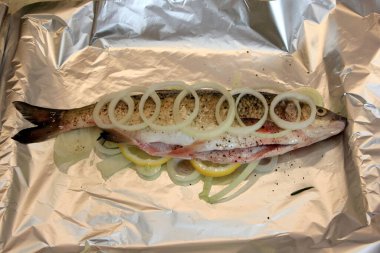 Limon, soğan ve baharatla doldurulmuş tuz yastığında taze balık. Tuzda pişmiş balık.