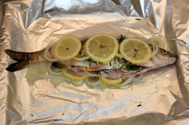 Limon, soğan ve baharatla doldurulmuş tuz yastığında taze balık. Tuzda pişmiş balık.