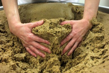 Ev yapımı ekmek hamuru. Elle yapılmış ve büyük bir tencere şeklinde. Kadının elleri ekmek hamurunu yoğuruyor..