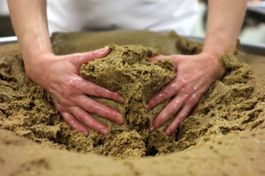 Ev yapımı ekmek hamuru. Elle yapılmış ve büyük bir tencere şeklinde. Kadının elleri ekmek hamurunu yoğuruyor..