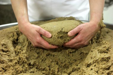 Ev yapımı ekmek hamuru. Elle yapılmış ve büyük bir tencere şeklinde. Kadının elleri ekmek hamurunu yoğuruyor..