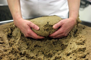 Ev yapımı ekmek hamuru. Elle yapılmış ve büyük bir tencere şeklinde. Kadının elleri ekmek hamurunu yoğuruyor..