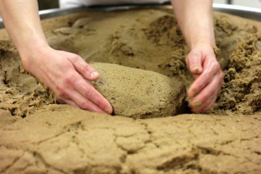 Ev yapımı ekmek hamuru. Elle yapılmış ve büyük bir tencere şeklinde. Kadının elleri ekmek hamurunu yoğuruyor..