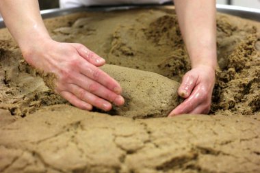Ev yapımı ekmek hamuru. Elle yapılmış ve büyük bir tencere şeklinde. Kadının elleri ekmek hamurunu yoğuruyor..