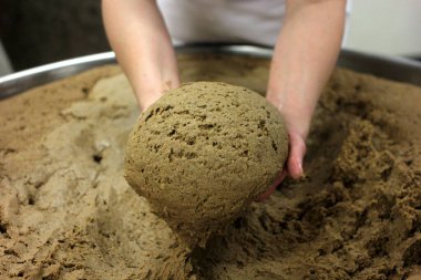 Ev yapımı ekmek hamuru. Elle yapılmış ve büyük bir tencere şeklinde. Kadının elleri ekmek hamurunu yoğuruyor..