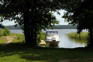 Yeşil tepeli göl, güneşli yaz günü gökyüzünde bulutlar Letonya 'da Usma Gölü. Göldeki tahta köprüler. İskelede beyaz yatlar 
