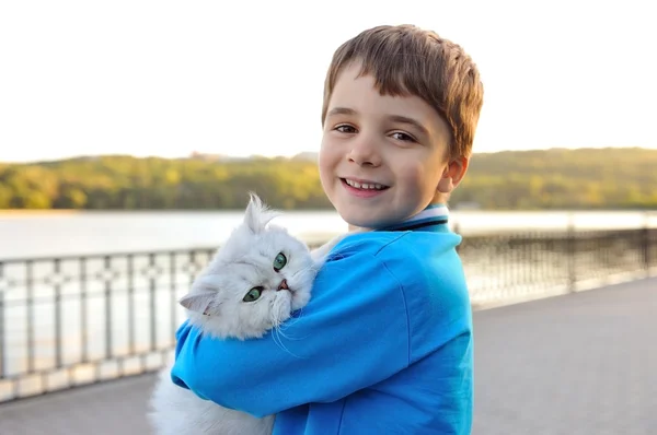 Witte kat, zittend op de handen van een jongen. — Stockfoto